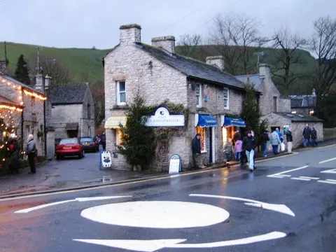 A stone corner shop in Castleton, with the hills behind